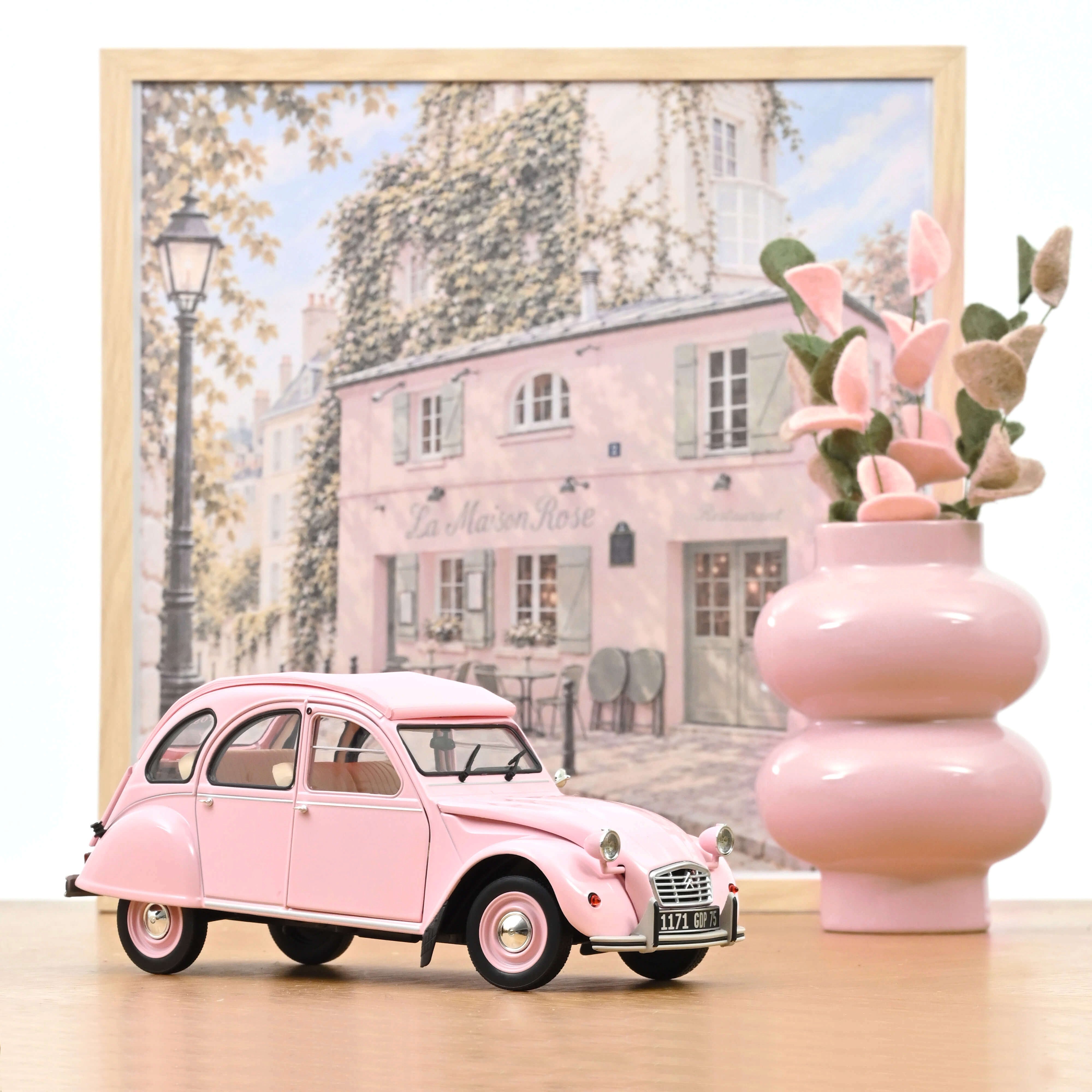 Voiture miniature Norev Citroën 2CV 1986 Paris mon amour rose poudré à l'échelle 1/18 sur fond décoratif parisien