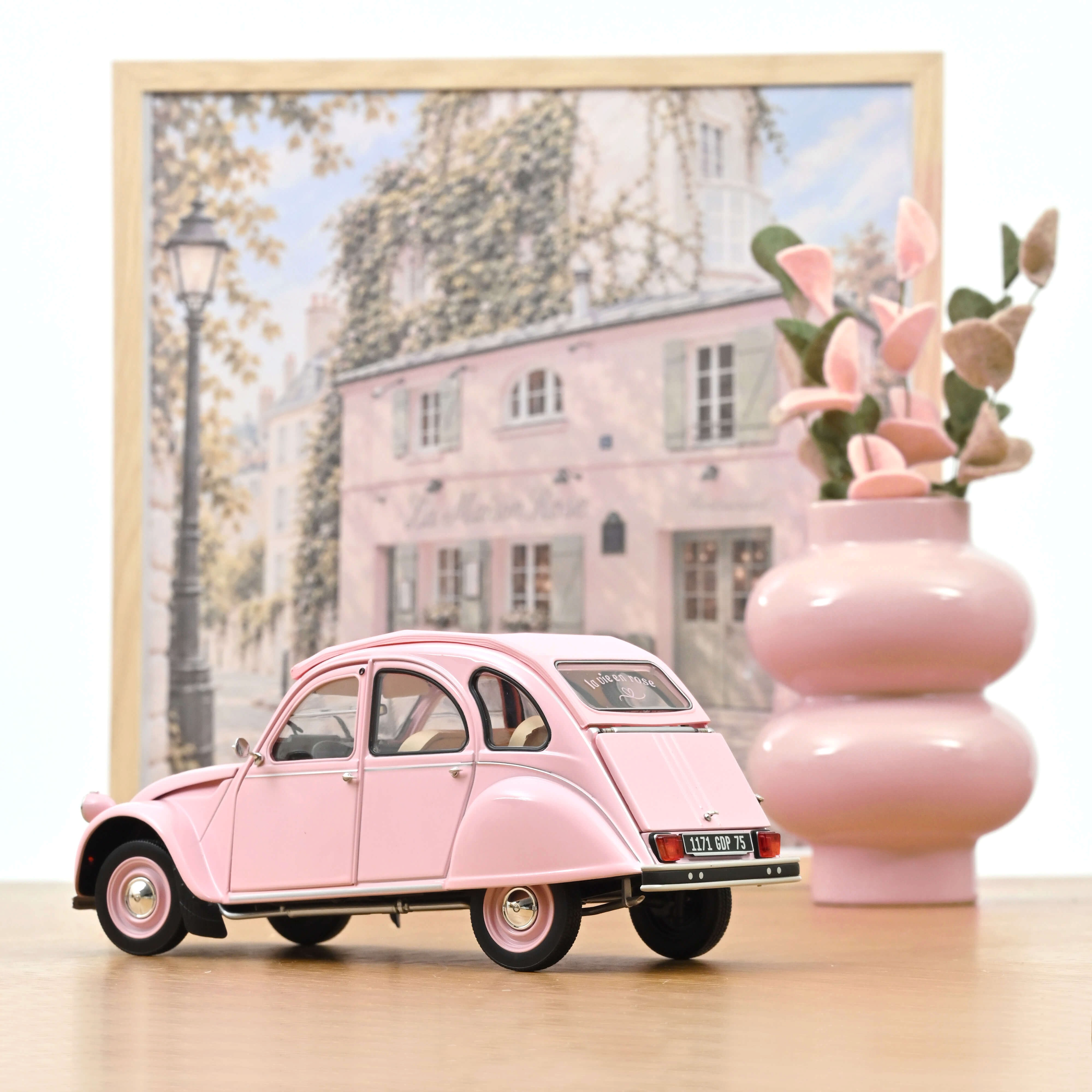 Voiture miniature Norev Citroën 2CV 1986 Paris mon amour rose poudré à l'échelle 1/18 sur une table en bois